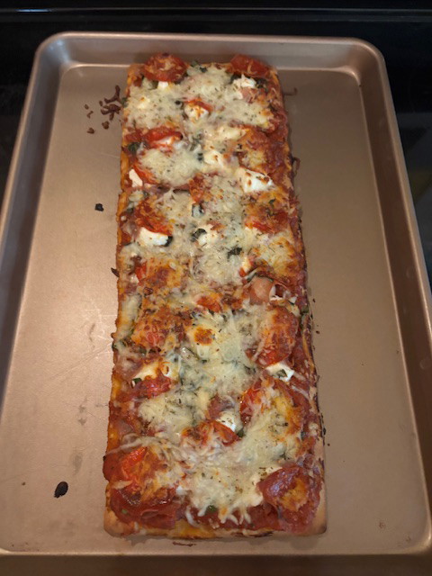 Image of Remove cookie sheet with pizza on it from oven and let cool for 3-5 minutes.