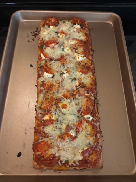 Image of Remove cookie sheet with pizza on it from oven and...