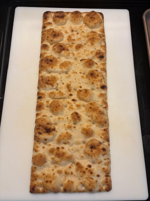 Image of Using a cutting board, place one pizza crust slab onto board.