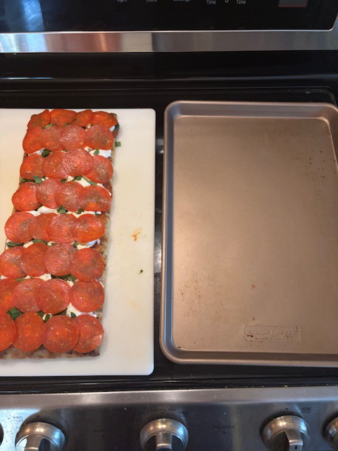 Image of Remove hot cookie sheet from oven using oven mitts and carefully transfer the pizza to the cookie sheet using 2 large flipping spatulas.