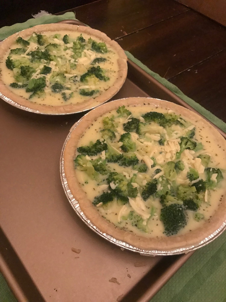 Image of In the partially baked gluten-free pie crusts, transfer the egg/broccoli mixture equally and in an even layer.