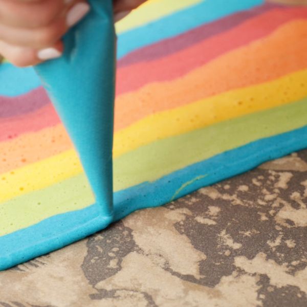 Image of Auf ein mit Backpapier belegtes Backblech ein Regenbogenmuster aufspritzen.