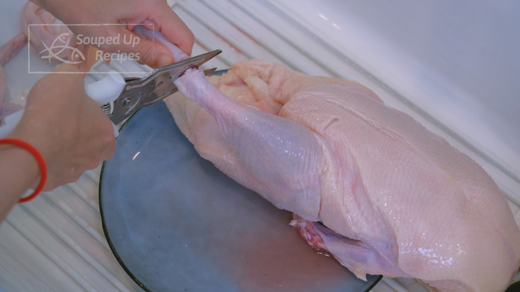 Image of Once the duck is defrosted, cut off the head but keep the neck; remove the wing tips and the feet because they burn fast while roasting. Rinse the duck thoroughly.
