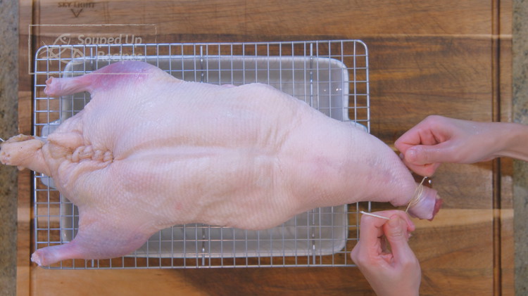 Image of Once done, tie the neck with kitchen twine to retain the air. Set the duck aside.