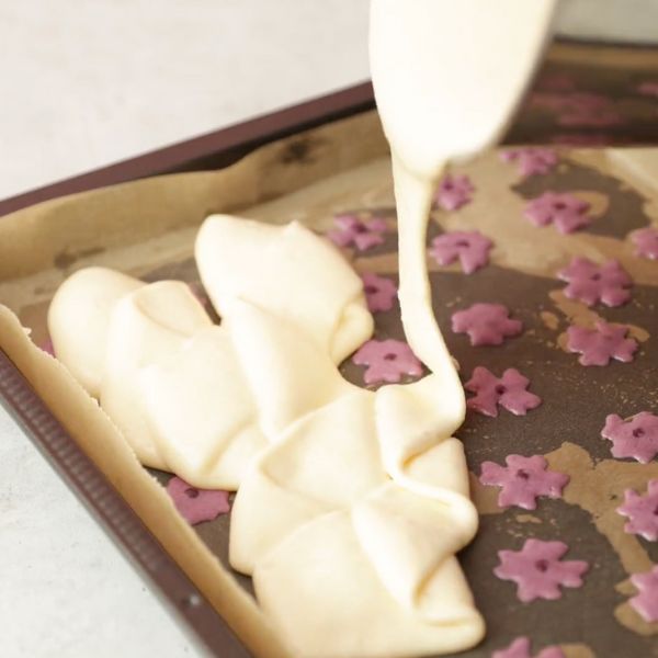 Image of Biskuitmasse gleichmäßig auf die vorgebackenen Blümchen streichen.