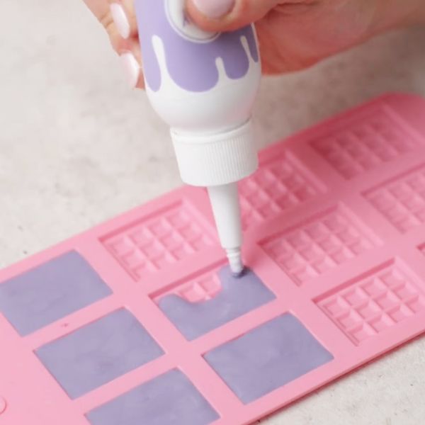 Image of In der Zwischenzeit kann der Happy Drip Soft Lilac nach Gebrauchsanweisung auf der Flasche erwärmt werden und in die Silikonform gegegen werden, damit die kleinen Schokoladentafeln vollständig auskühlen können, diese können auch ins Gefrierfach gelegt werden.						