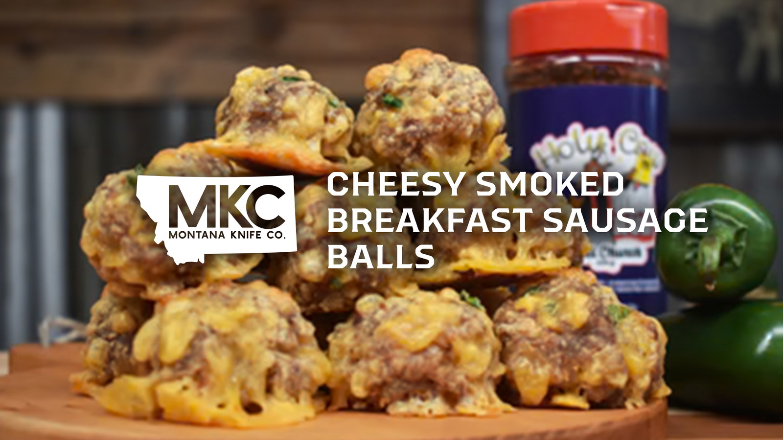 Pile of cheesy smoked breakfast sausage balls on wooden cutting board next to jar of seasoning.