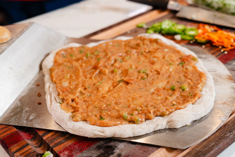 Image of Top the par-cooked dough with beans, meat, and cheese in...