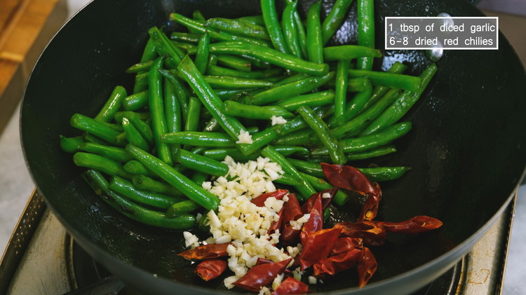 Image of Add the diced garlic and dried red chilies and stir for a couple of minutes or until fragrant. Remove the green beans to the side and clean up the wok because we gonna cook the beef.