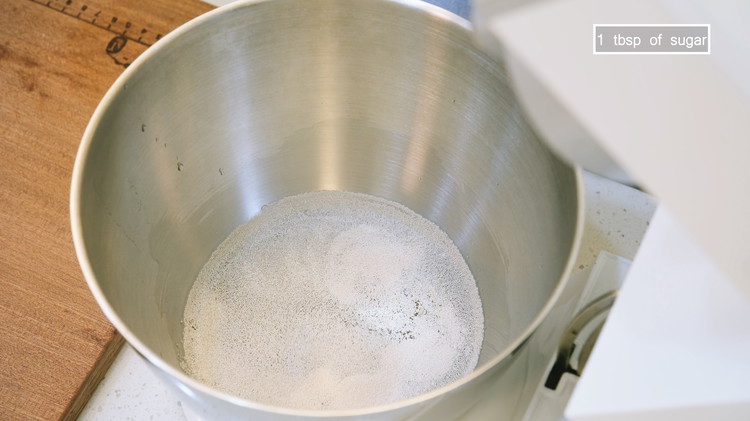 Image of Combine 300 grams of lukewarm water, 2 tsp of instant yeast, and 1 tsp of sugar in a bing mixing bowl. Stir until the yeast is well distributed. 