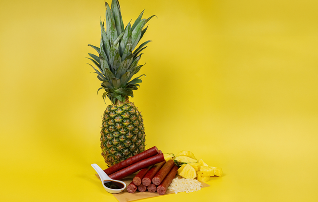 Pineapple Teriyaki Snack Sticks made with PS Seasoning No. 853 Pineapple Teriyaki Snack Stick Seasoning, shown with fresh pineapple, teriyaki sauce, and cooked rice on a yellow background.