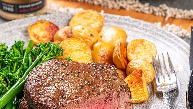 Sizzling ribeye steak in cast iron pan with herbs and butter
