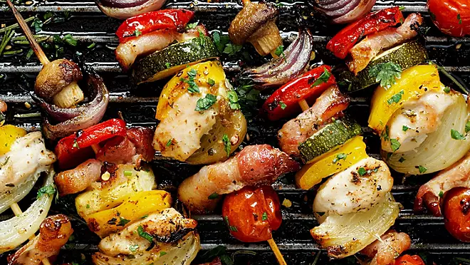 Char-grilled veggie skewers with peppers, onions, and zucchini on a wooden board