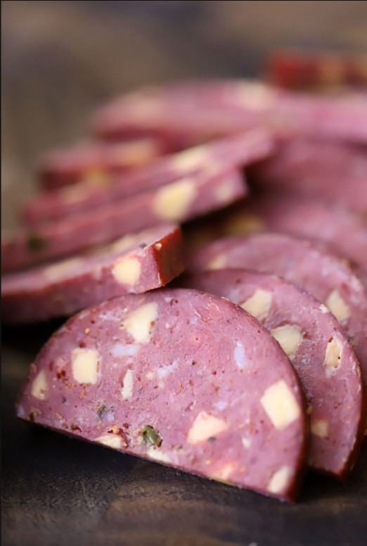 Jalapeño cheddar venison summer sausage sliced with cheese on board – perfect for wild game charcuterie and snack trays