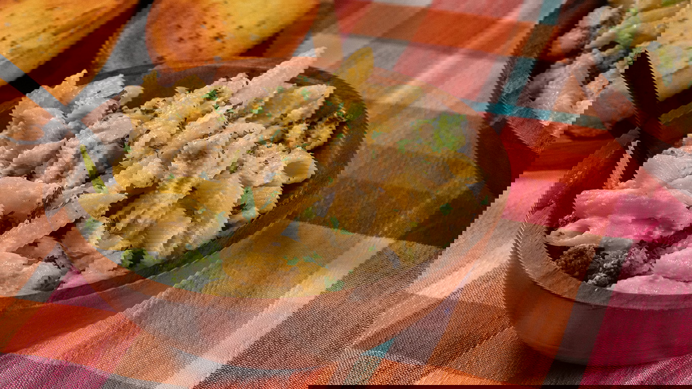 A wood bowl of tender penne pasta, chunks of Halal chicken, and broccoli and coated in richly creamy homemade alfredo sauce. Served alongside garlic bread.