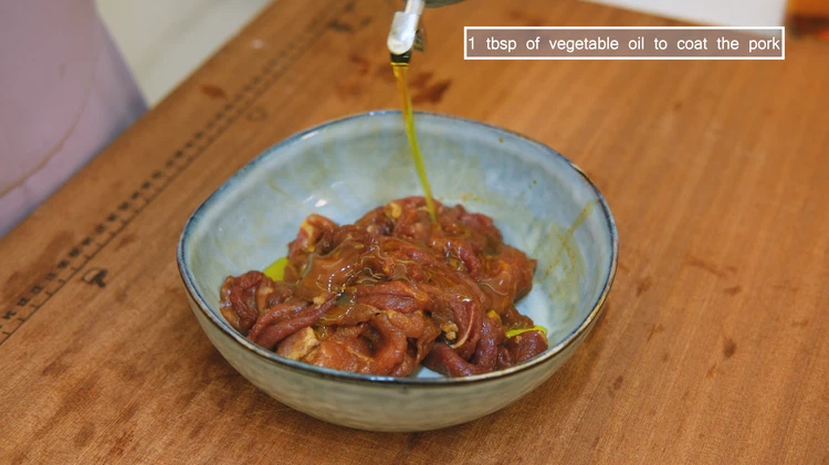 Image of Drizzle in 1 tbsp of vegetable oil and mix to coat the pork. This helps to separate the meat slices and prevent them from sticking to each other while cooking. Set the meat aside.