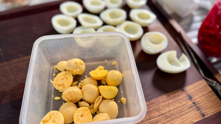 Image of after hard boiling your eggs and mashing the yolks separately, add all ingredients into a bowl (minus bacon) and mix until smooth and fully incorporated