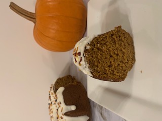A single slice of moist spiced pumpkin bundt cake, topped with icing and nuts, resting on a dessert plate.