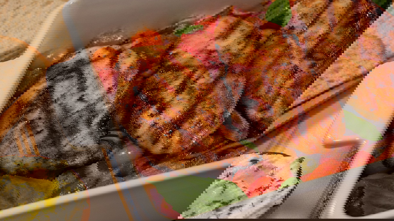 Top down shot of juicy halal grilled chicken served on a bed of sliced baked tomato, onion, peppers, and fresh basil. Served with sliced sourdough and ricotta cheese.
