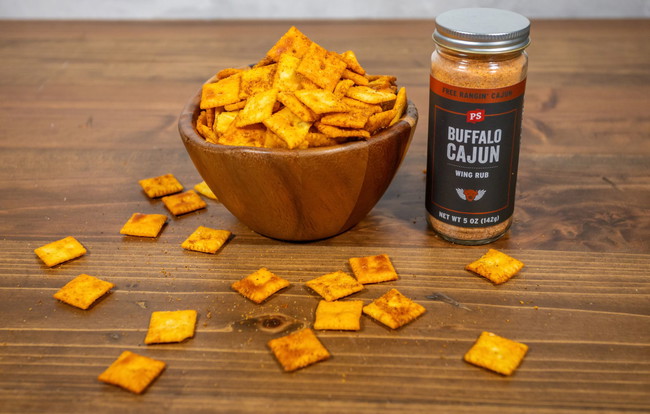 Wooden bowl filled with smoked Cheez-Its seasoned with PS Seasoning Buffalo Cajun Wing Rub, surrounded by scattered crackers on a wooden table. Buffalo Cajun smoked Cheez-Its, PS Seasoning snack recipe, smoked cheese crackers, spicy Cheez-It recipe, Pro Max smoker snacks, Cajun cheddar crackers, game day smoked snacks