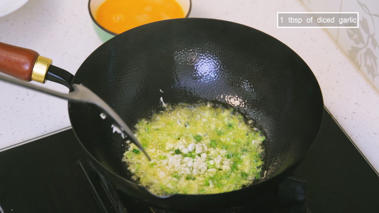 Image of Swirl the oil to coat the wok and create a nonstick layer. Add half of the diced scallions and 1 tablespoon of minced garlic and stir for just a few seconds.