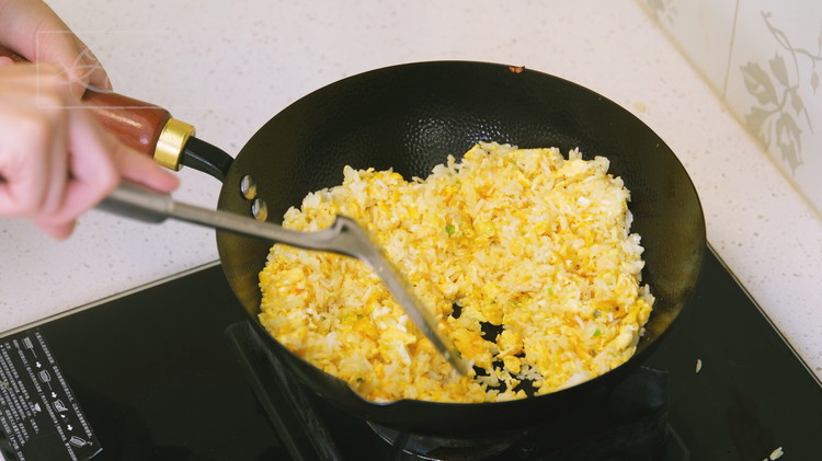Image of Once the egg is mostly set, drizzle a bit more oil around the edges of the wok, then add the cooked rice. Break up any clumps until every grain is loose and separated. Continue to stir the rice for 3...