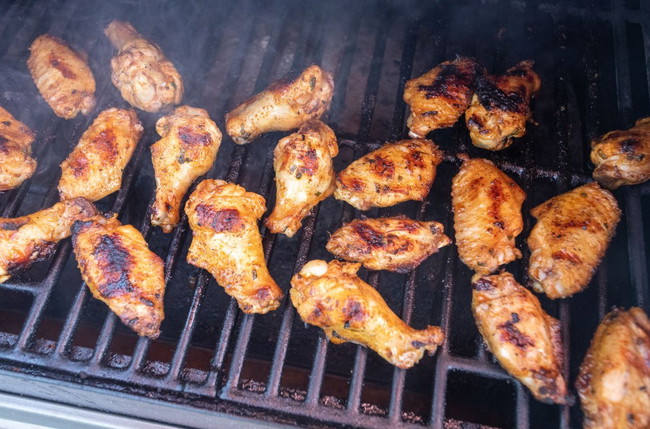 Crispy grilled chicken wings cooking over medium heat on a gas grill, seasoned with dry rub for golden brown skin and smoky flavor—an easy no-fail recipe perfect for BBQs, tailgating, and game day.