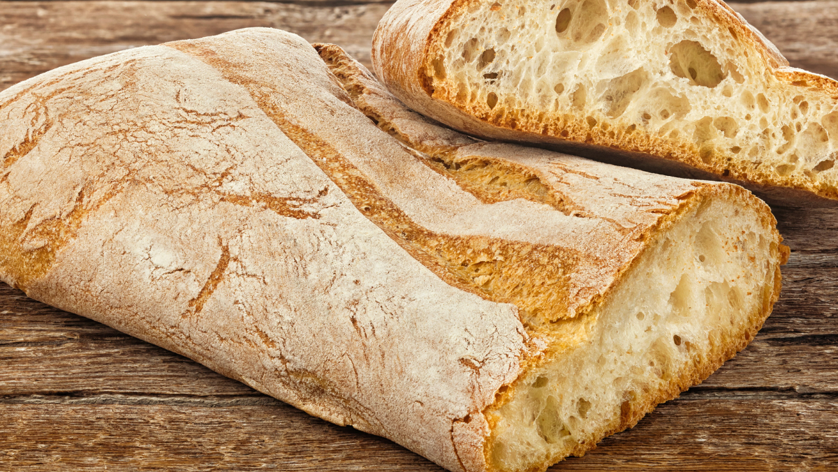 Loaf of ciabatta bread with a slice cut off on a wooden surface