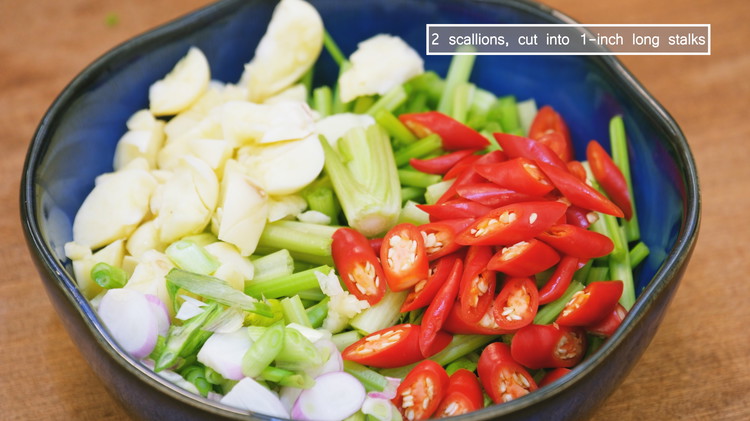 Image of While waiting, cut the Chinese celery stems into 1-inch long pieces, peel and chopped the garlic, dice the Thai bird eye chilies, chop the ginger, and cut the scallions into 1 inch long pieces. Separate the green and white parts.