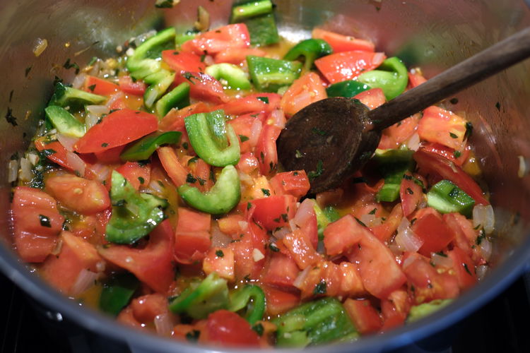 Image of Add chopped tomatoes and green peppers to the pot.