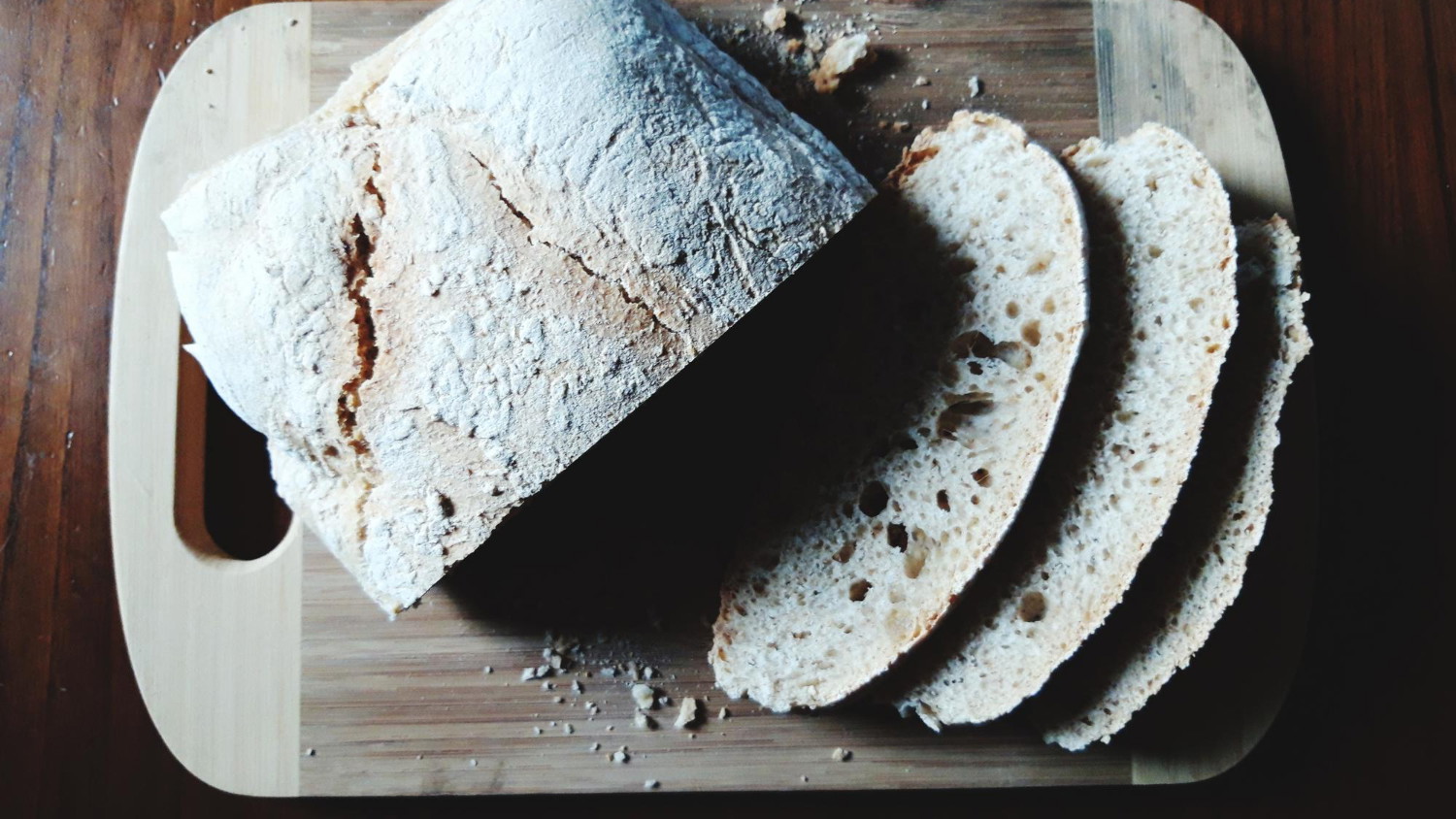 Load of no-knead bread on a wooden cutting board with a brown background