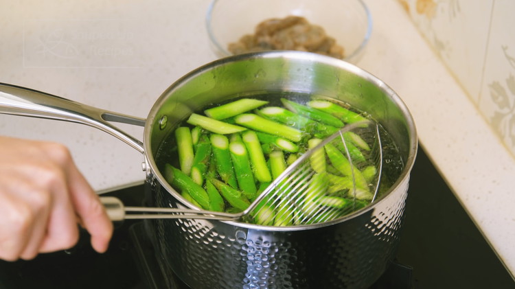 Image of Bring 2 liters of water to a boil and add a drizzle of oil. Blanch the asparagus for 15 seconds. Then take it out and set it aside to drain.