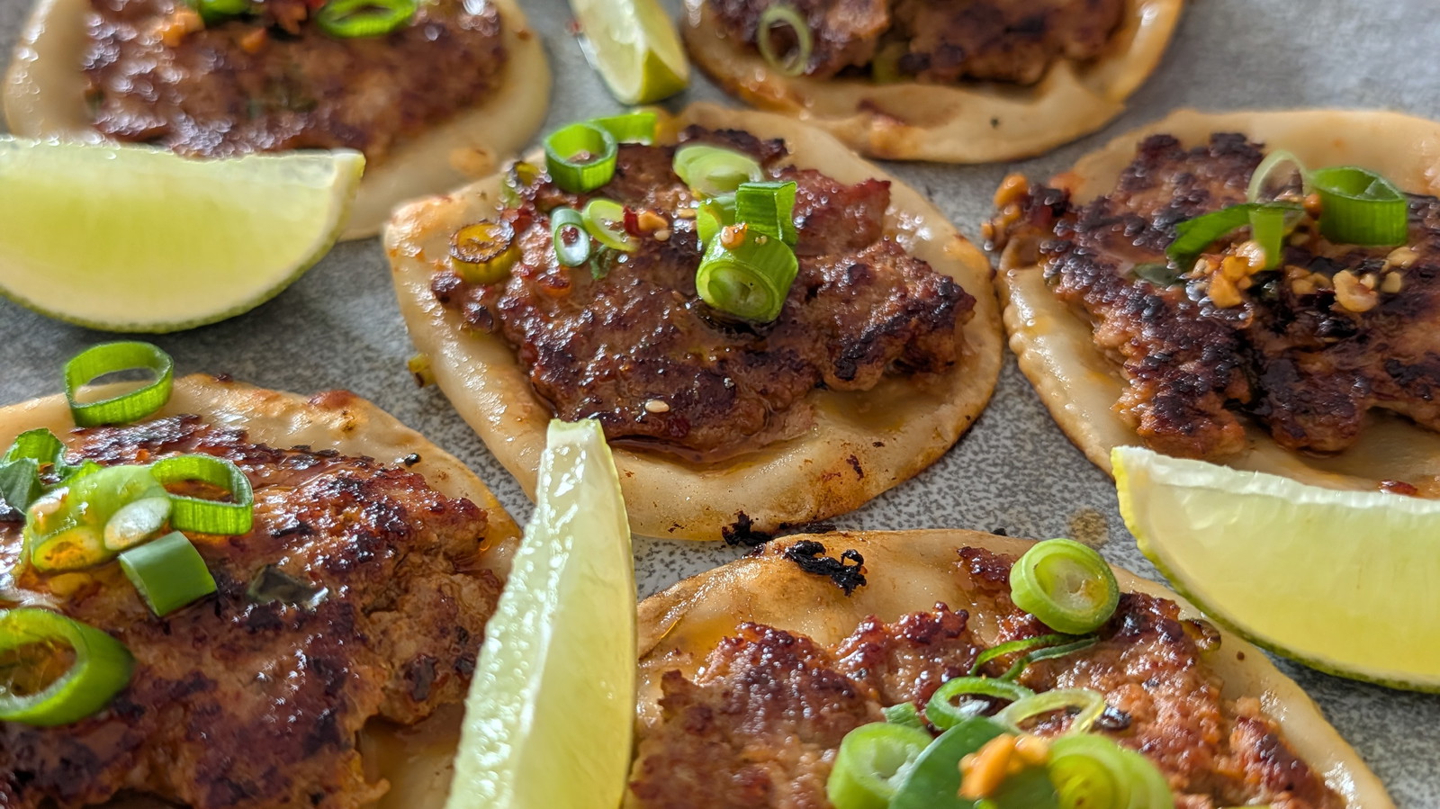 golden brown smash dumplings on a plate with wedges of lime and K-Pop Dust shaker in the background