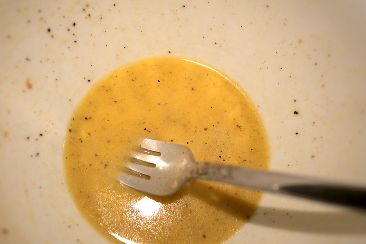 Image of Add vinegar (or the above vinegar/shallot mix), mustard, melted butter, and a few rounds of fresh ground black pepper to the mashed anchovies and whisk to emulsify. 
