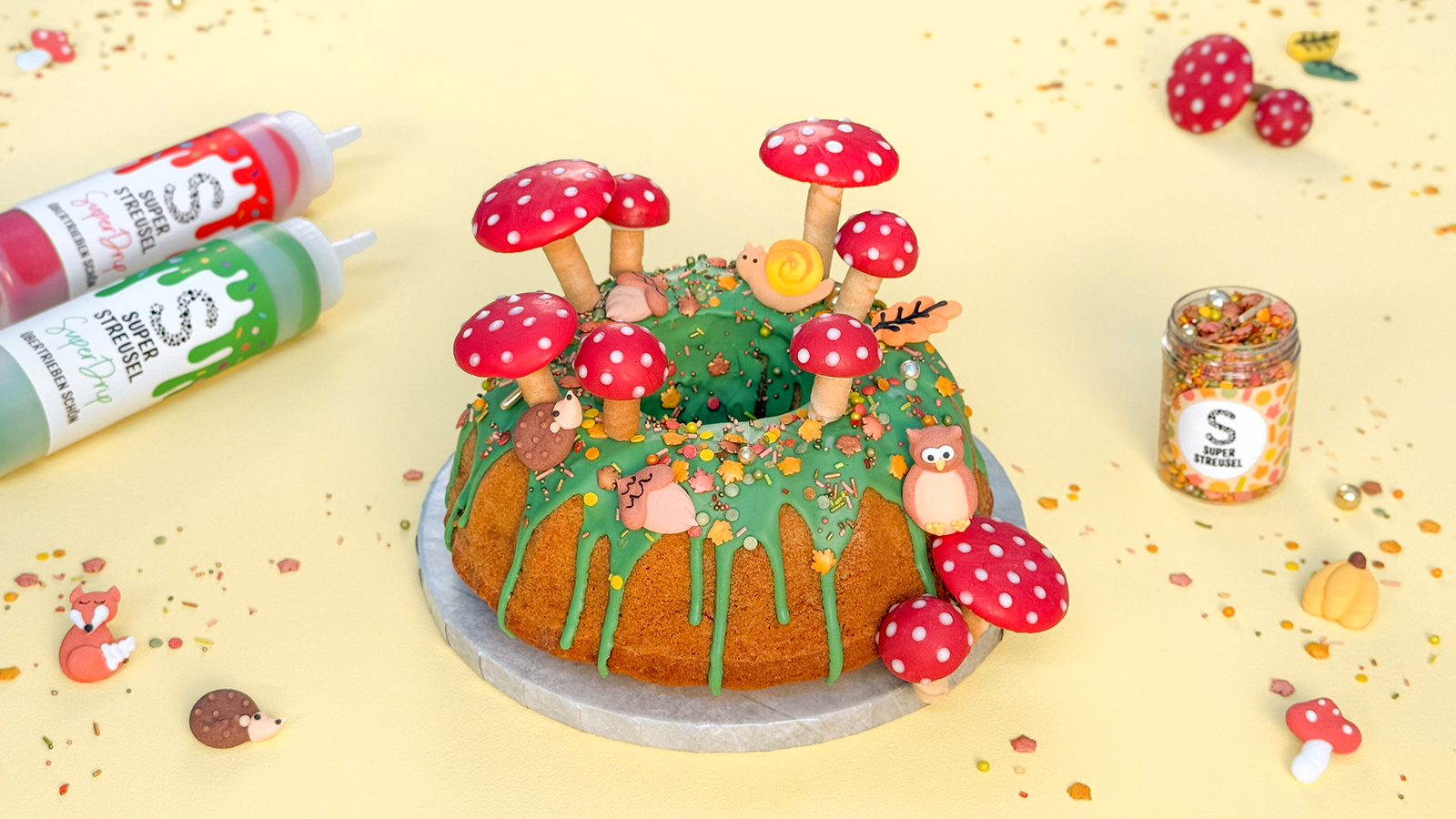 Herbstlicher Gugelhupf mit grünem Drip, Streuseln, Fliegenpilzen & WaldWichteln verziert. 🍄✨