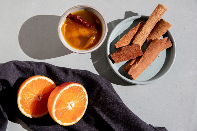 Zelfgemaakte sinaasappel-kaneel siroop met vers sinaasappelsap en Ceylon kaneelstokje, perfect voor desserts, koffie of cocktails