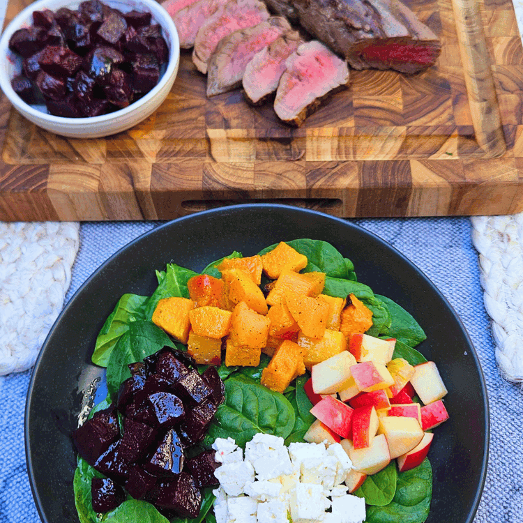 Image of Assemble the salad by placing a handful of the baby spinach in each bowl, and arrange the squash, beets, apples, feta, and nuts in the bowl.