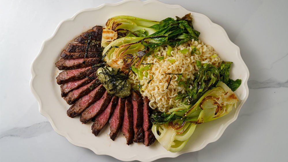 Ramen bok choy, noodles, ny strip steak on white plate 