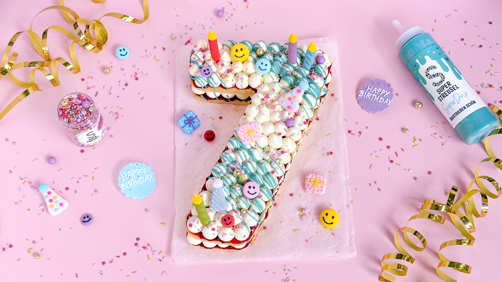 Number Cake in Siebenform mit Vanillecreme-Tuffs, rosa Marmeladenschicht, SuperDrip Türkis, StreuselMix HochSollstDuLeben und SuperDinger HippHippHurra.