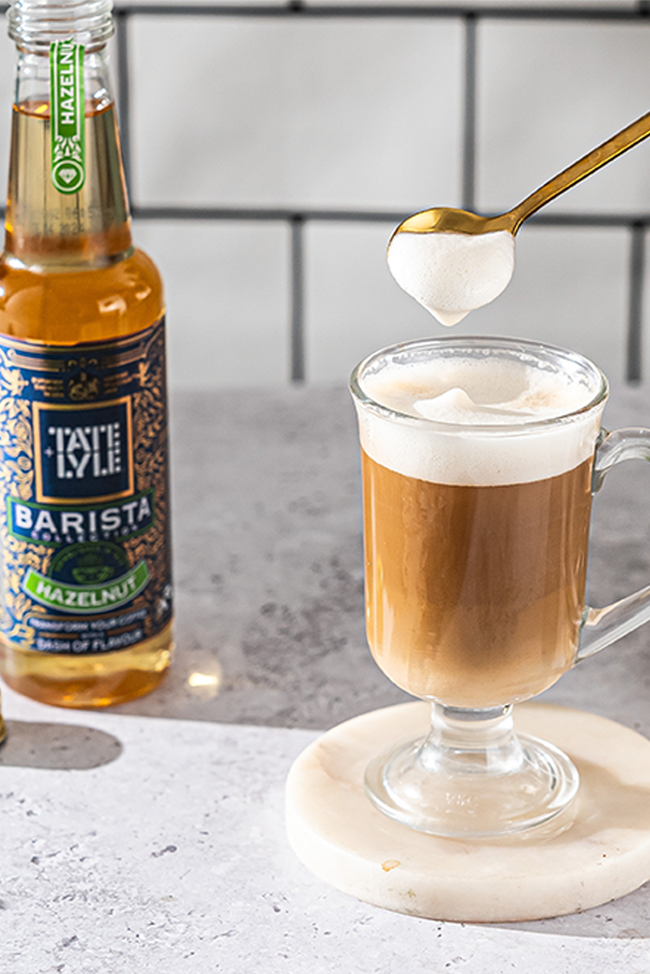 Coffee topped with frothy milk and served with Tate & Lyle Hazelnut flavoured syrup