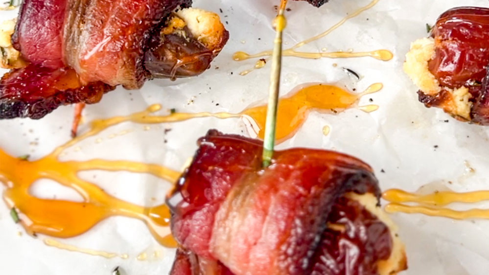bacon-wrapped date on a toothpick with hot honey drizzle on baking paper
