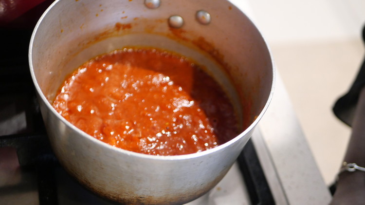 Image of Into whisk together the water or stock, tomato purée, tomato paste, cumin, ¼ tsp harissa paste, bay leaves, garlic, parsley, coriander, salt, and pepper. Bring to a simmer and adjust seasoning.