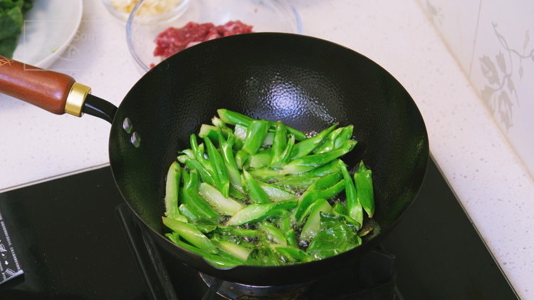 Image of Turn the heat to high and preheat the wok until smoking hot. Add a big drizzle of oil and swirl it around to create a non-stick coating. Toss in the Gailan stems and stir for a couple of minutes.