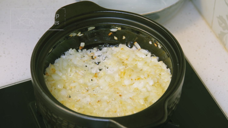 Image of Preheat the clay pot until hot. Add 4 tablespoons of butter and the diced sweet onion, and stir-fry over medium-low heat until the onions are soft and the edges are slightly browned.