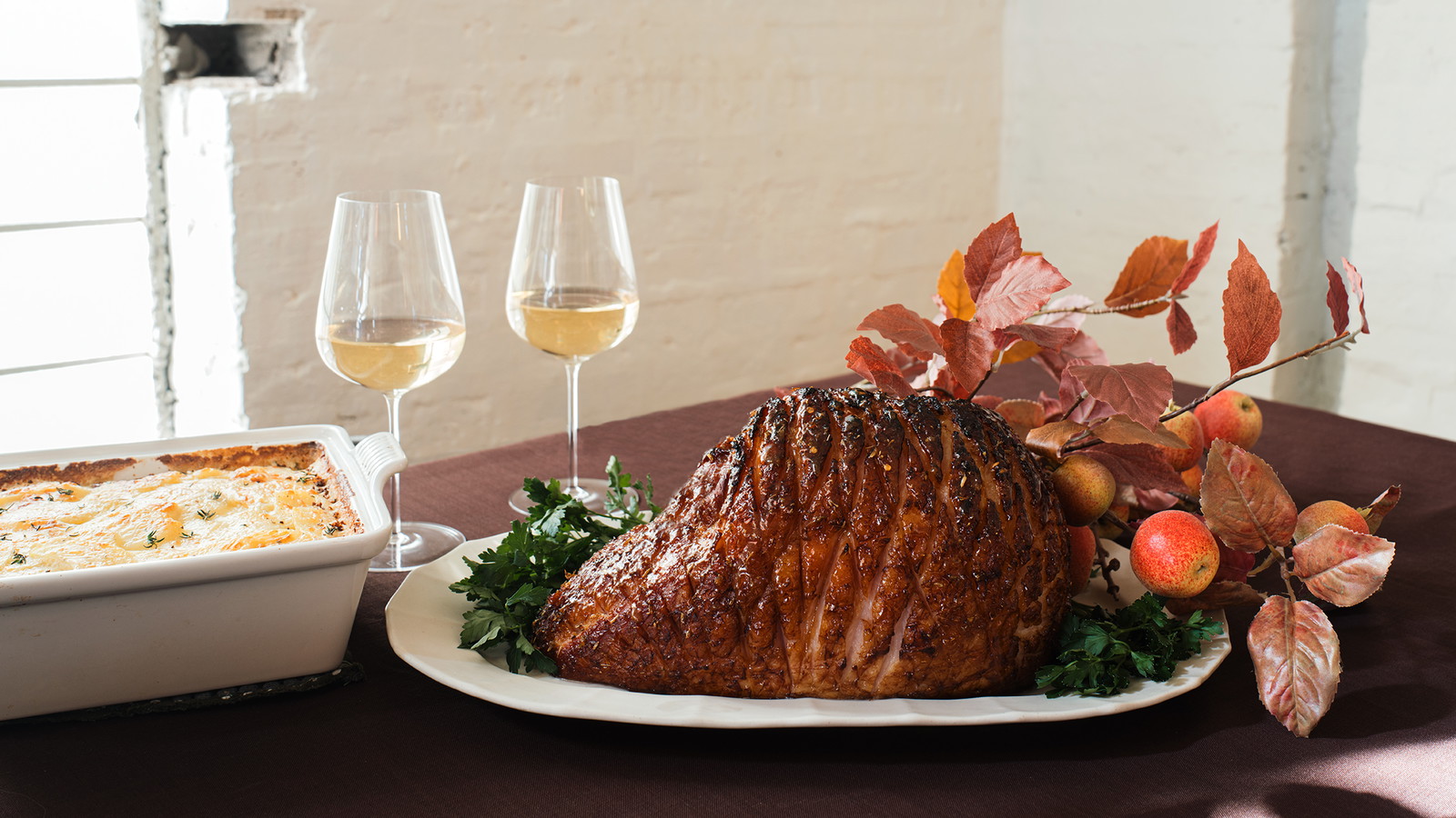 Honey Glazed Half Ham on table with sides and glasses of wine 