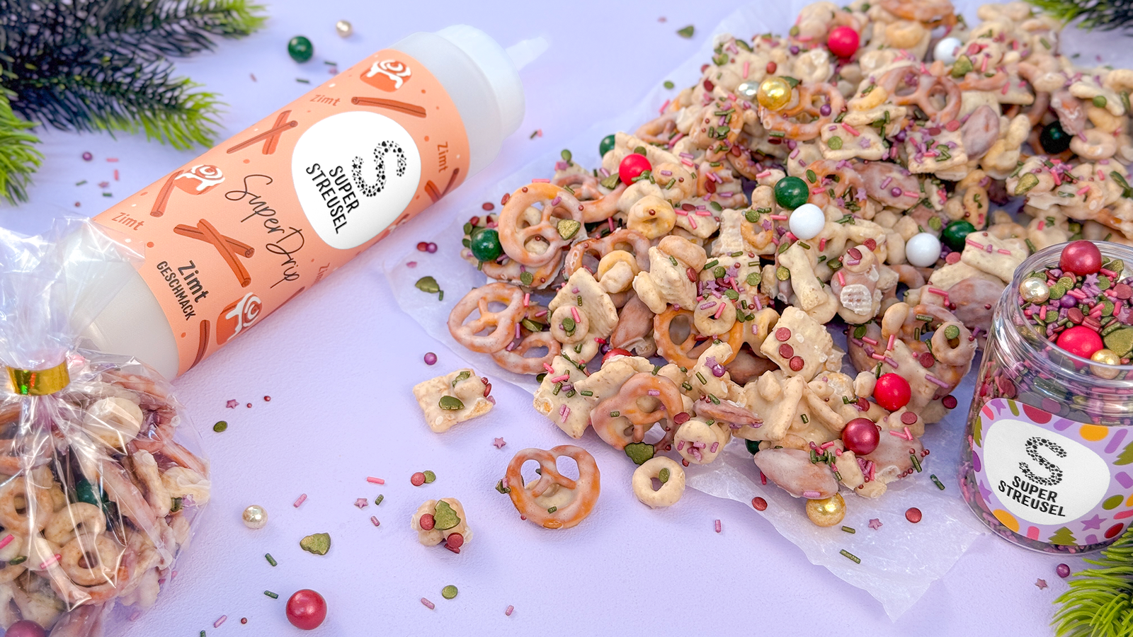 Christmas Crunch van ontbijtgranen, noten en mini zoutpretzels, omhuld met Kaneel SuperDrip, gedroogd op de SuperBackmatte en gedecoreerd met StreuselMix NightGlow en KugelMix ChocoBalls ClassyChristmas. Knapperige kerstsnack.
