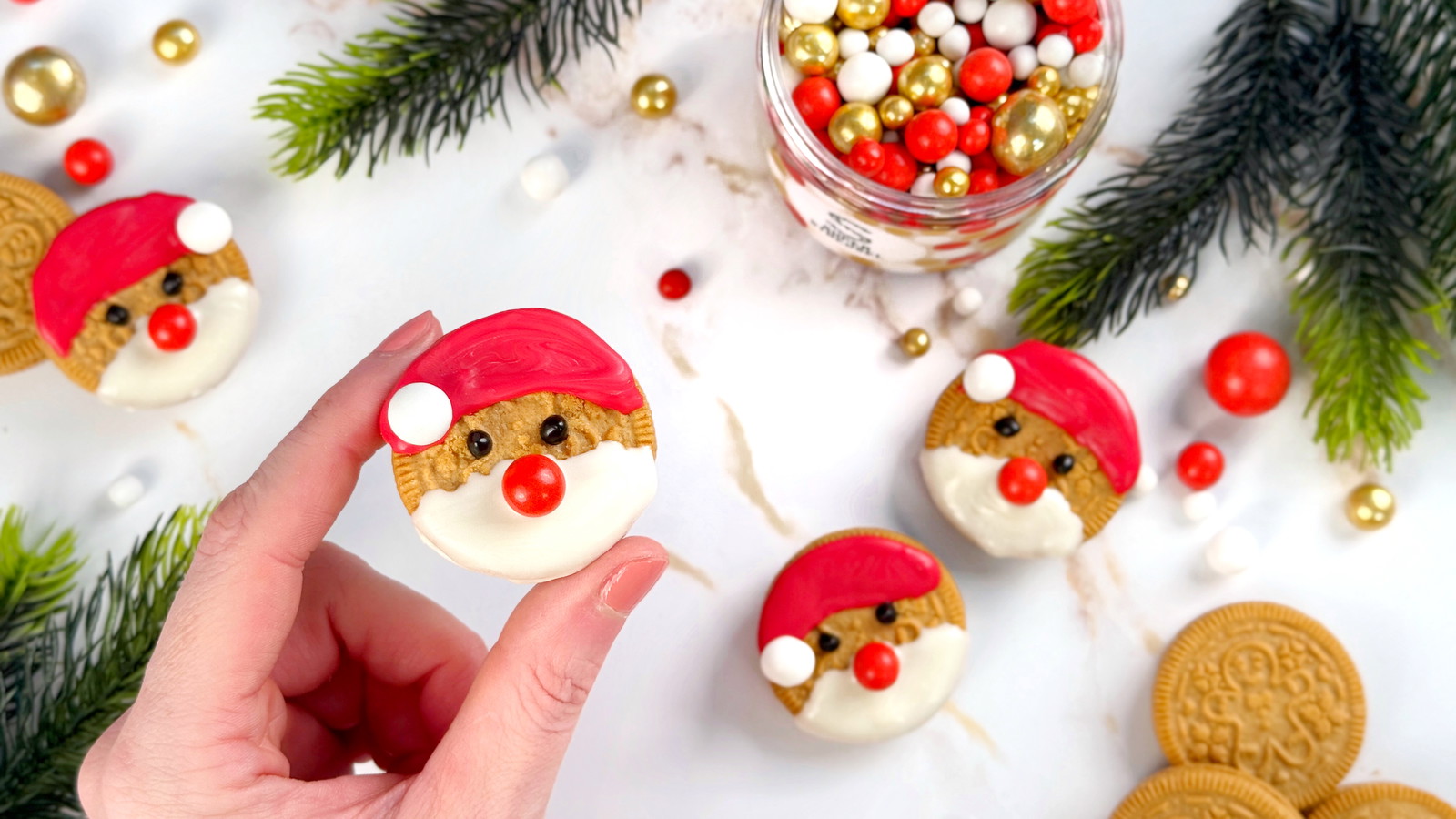Keks-Nikoläuse aus hellen SandwichCookies, dekoriert mit rotem, weißem und schwarzem SuperDrip sowie KugelMix GlockenSpiel als Nase und Bommel. Süße Weihnachtskeks-Deko