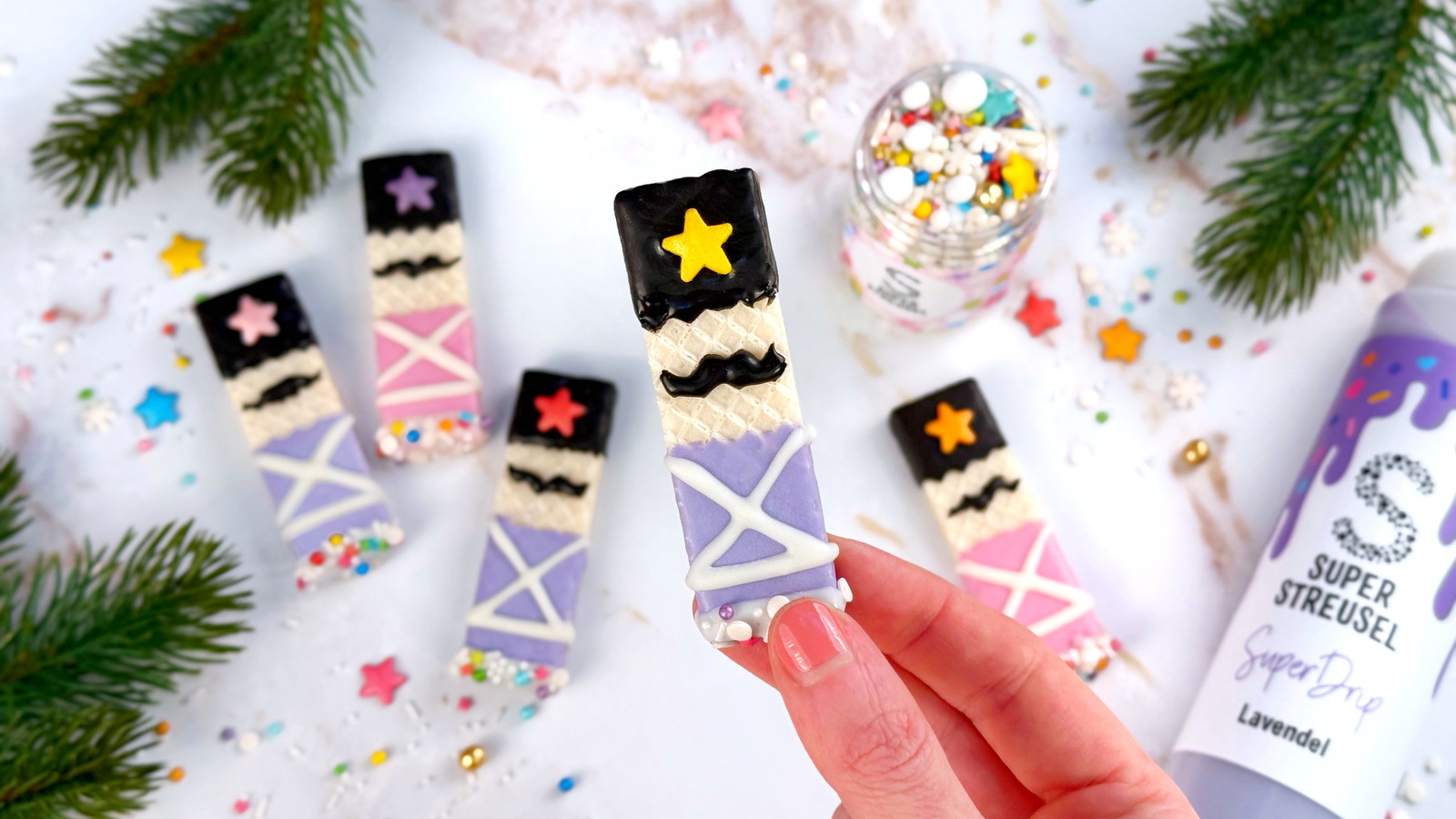 Nussknacker-Waffeln aus gefüllten Waffelkeksen, dekoriert mit schwarzem, weißem, rosa und lavendelfarbenem SuperDrip sowie StreuselMix OhDuFröhliche. Bunte Weihnachts-Waffel-Deko mit Stern und Schnurrbart.