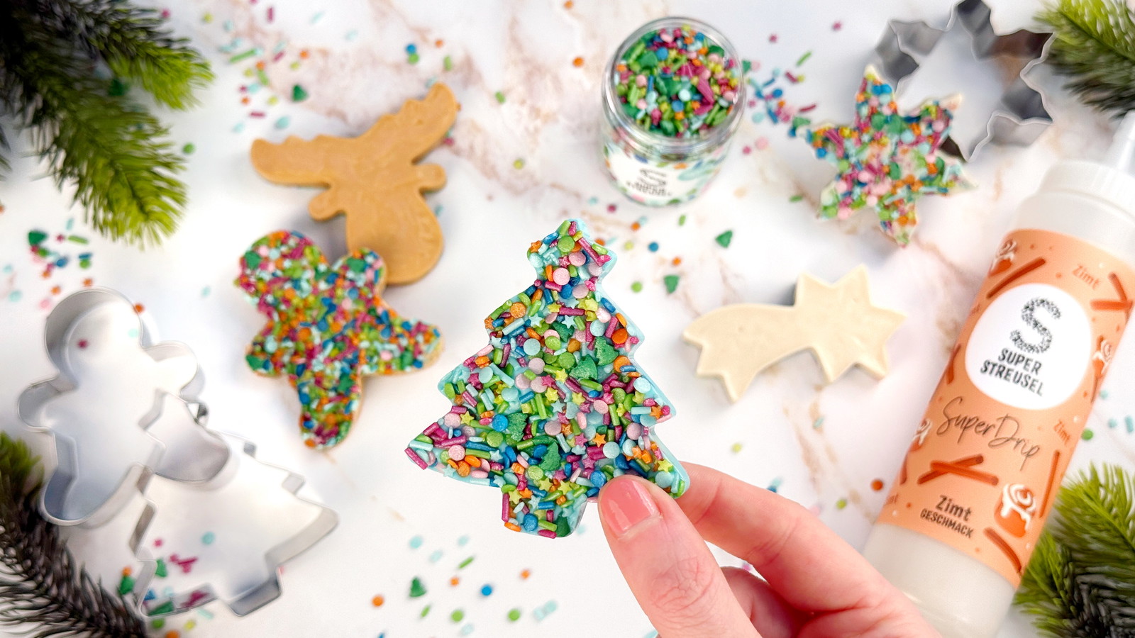 SchokiStreuselPlätzchen aus Ausstechformen, gefüllt mit SuperDrip Zimt, Salted Caramel und Bubblegum, verziert mit StreuselMix OhTannenbaum. Schnelle Weihnachtsplätzchen ohne Backen.