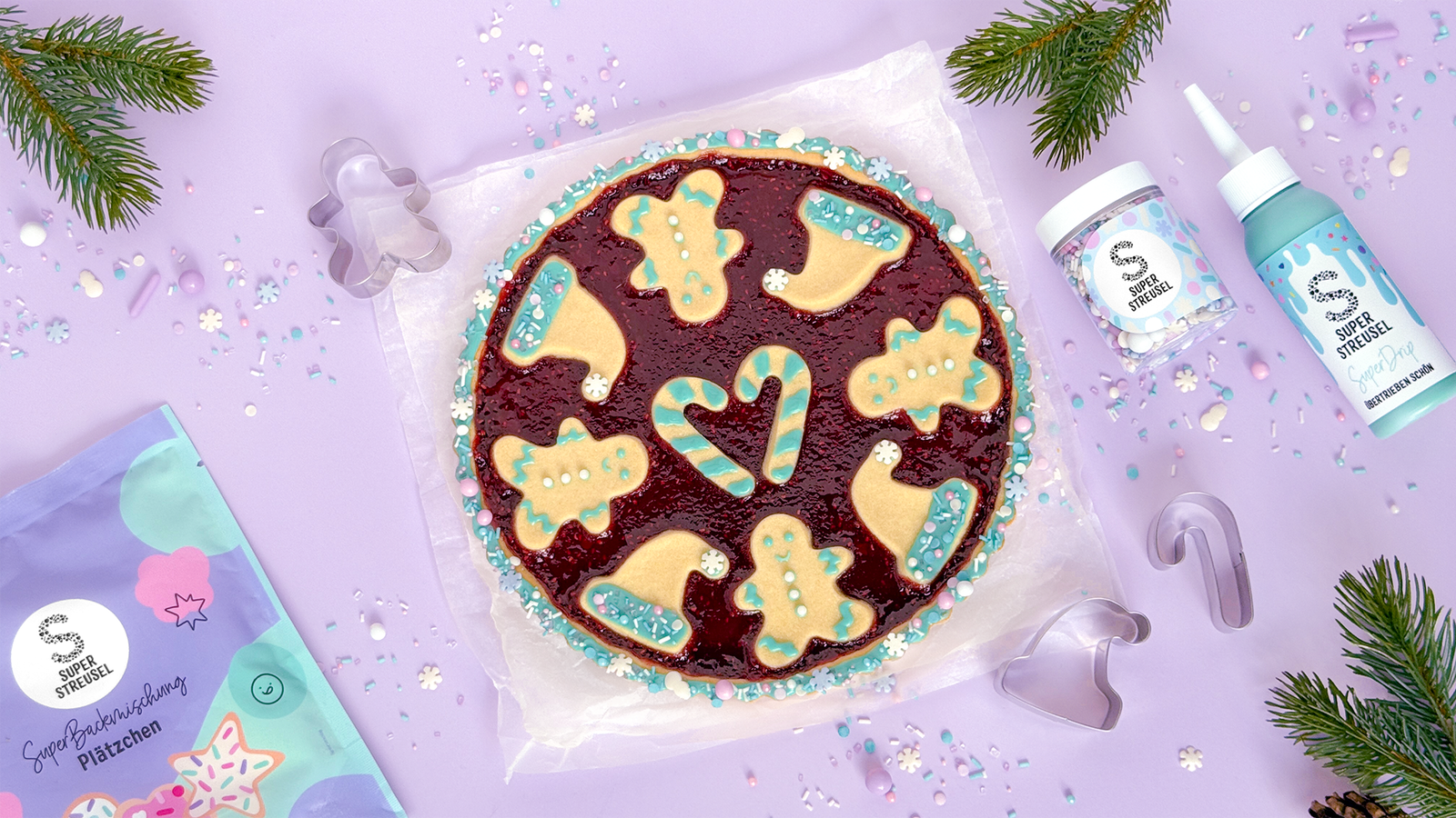 Weihnachtliche XMas-Tarte mit Himbeermarmelade-Füllung, dekoriert mit Plätzchen in Form von Weihnachtsmütze, Lebkuchenmann und Zuckerstange, verziert mit SuperDrip Eisblau und StreuselMix SchneeStürmchen.